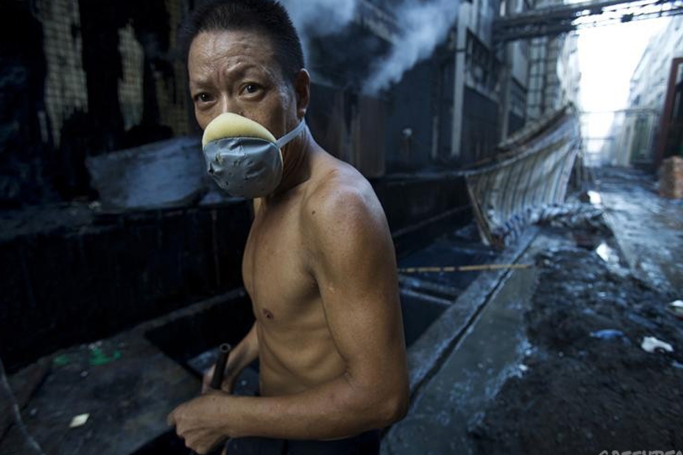 A worker at a denim factory. The air is so toxic that he has to wear a mask.